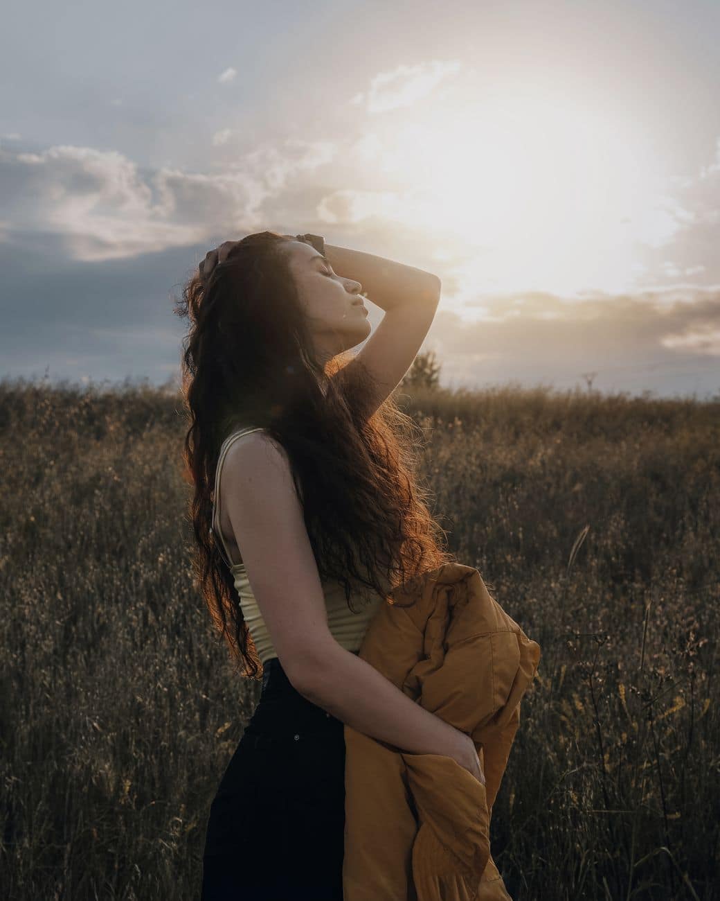 young woman embracing sunset in serene field